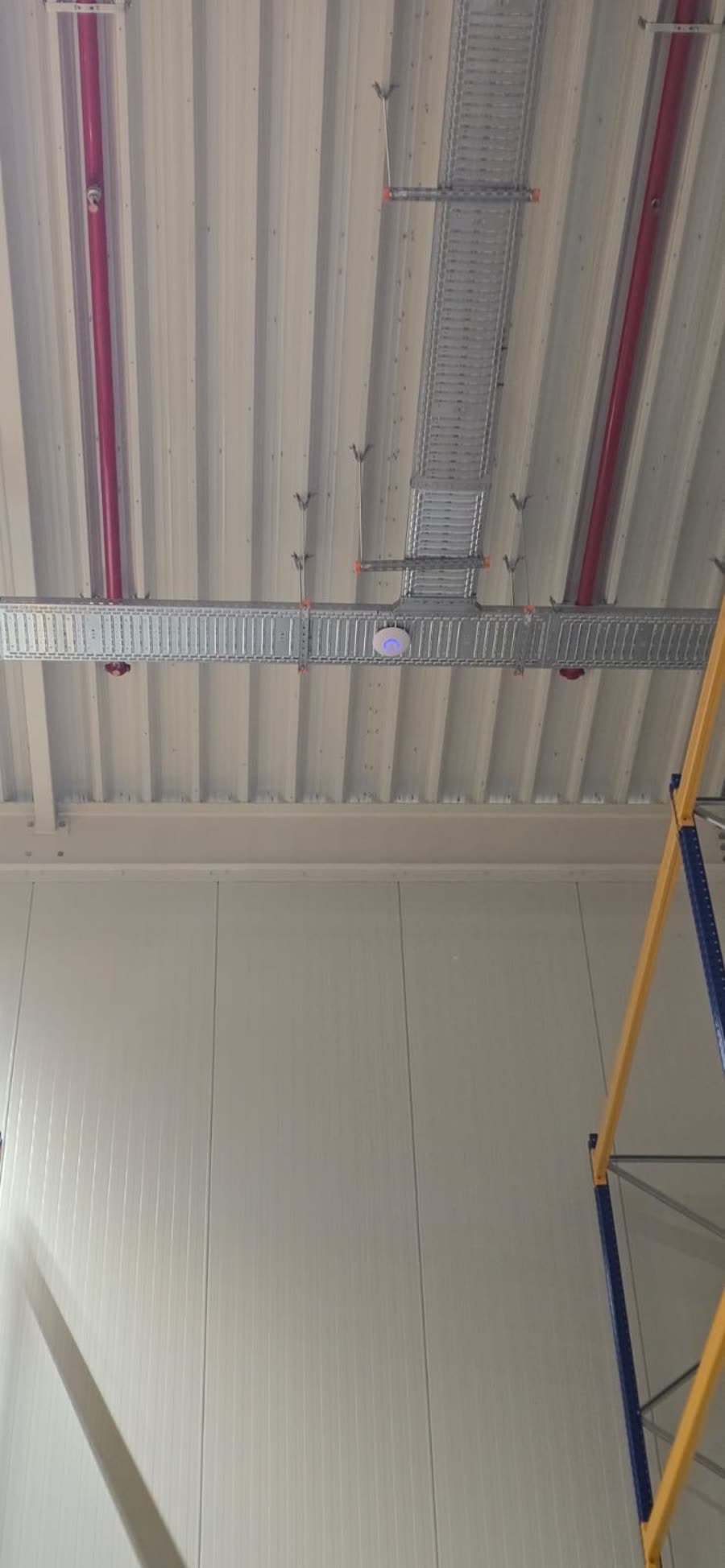 Wifi-accesspoint gemonteerd in een kabelgoot boven de stellingen.