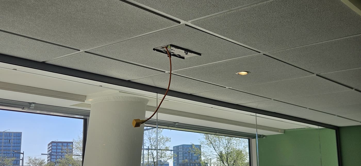 Accesspoint aan het plafond van een kantoorruimte met glasgevel.