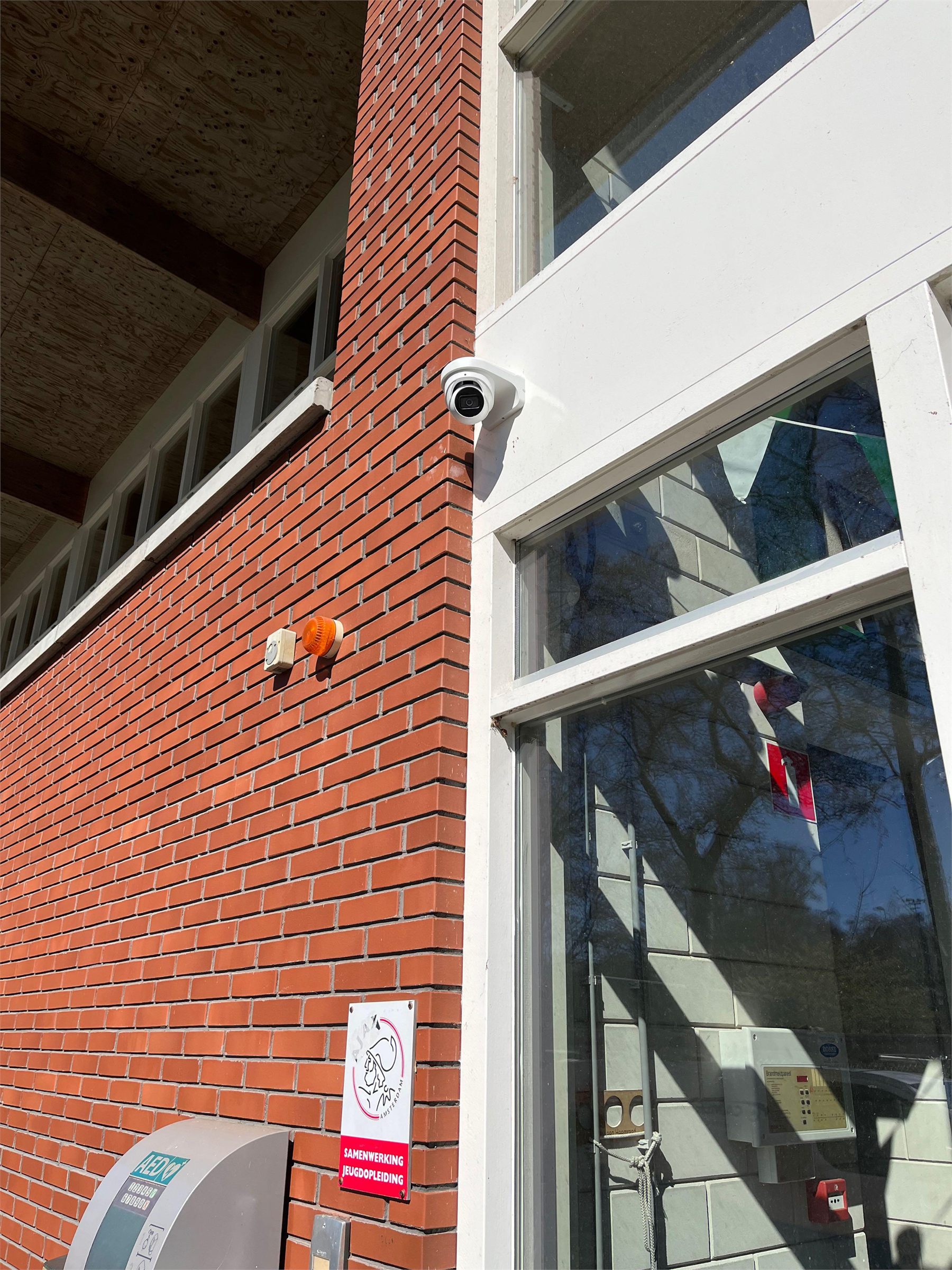 Beveiligingscameras aan de bakstenen gevel van een gebouw met meerdere woonlagen.