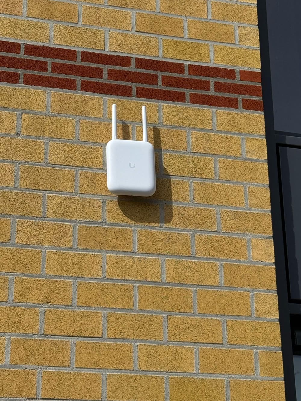 Buiten-accesspoint aan een bakstenen gevel.