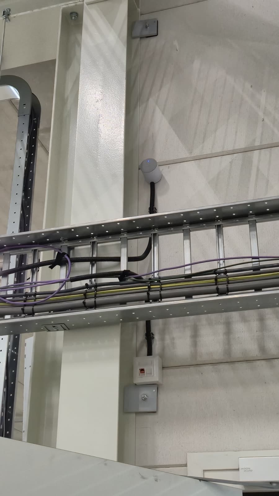 Beveiligingscamera boven een kabelgoot in een industriele hal.