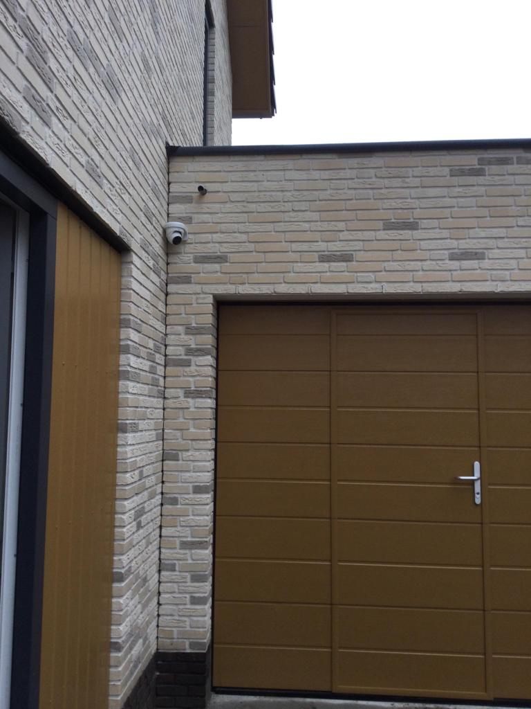 Beveiligingscamera en video-intercom naast de ingang van een woning.