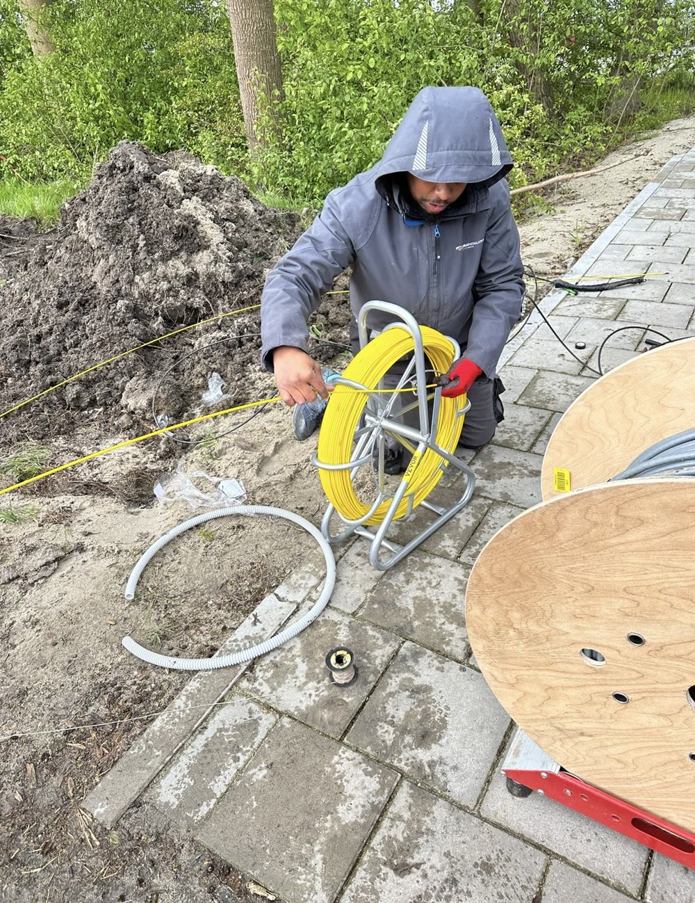 Monteur trekt een glasvezelkabel door met een rijgveer.