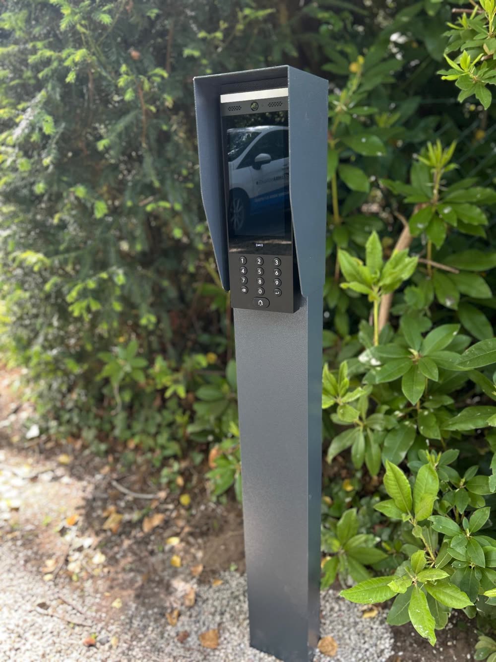 Vrijstaande intercomzuil met scherm en keypad naast de oprit.