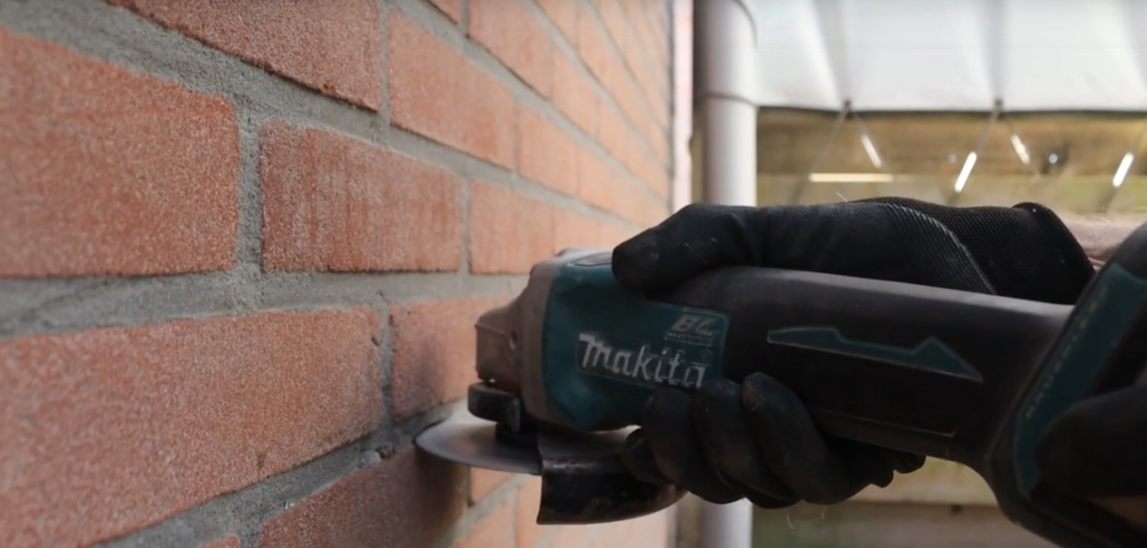 Kabelroute in de voeg van een bakstenen muur wordt netjes afgewerkt.