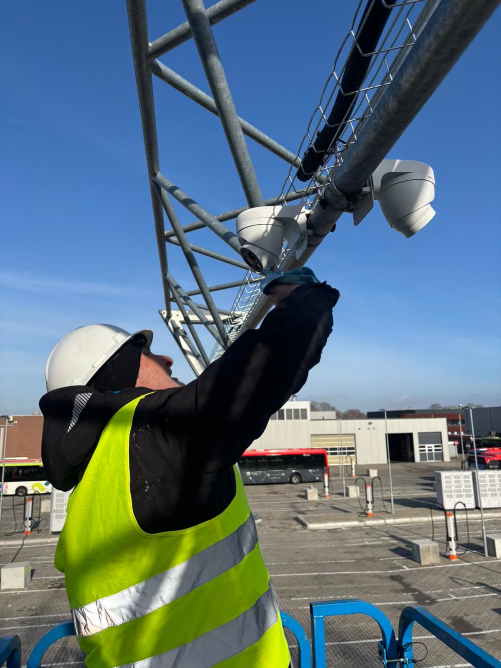 Monteur monteert een beveiligingscamera boven in een mast.