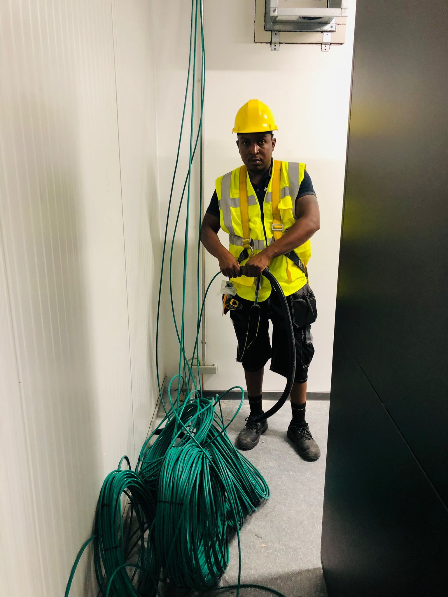 Monteur werkt aan een bundel groene netwerkkabels.