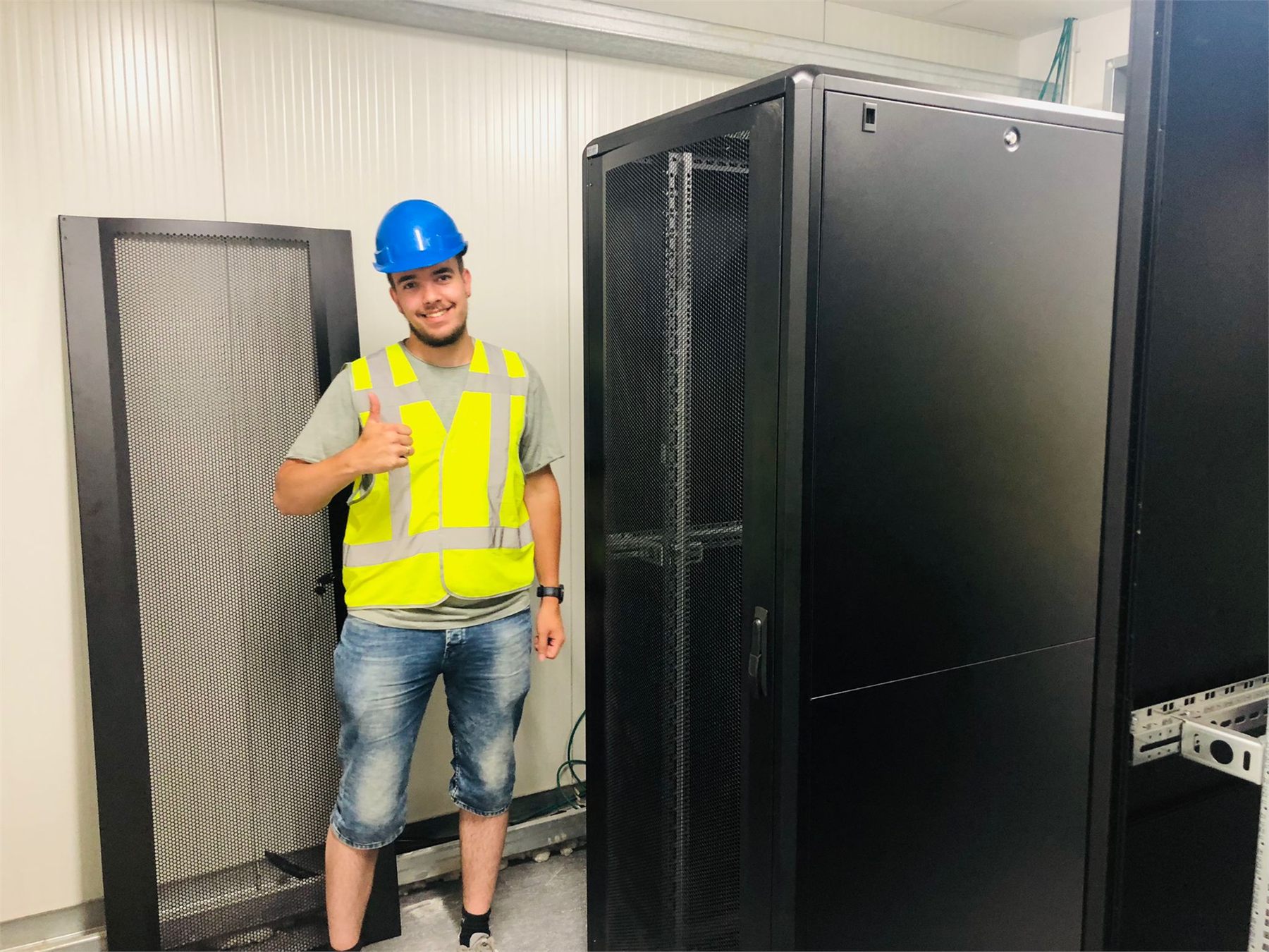 Monteur bij grote serverkasten in een technische ruimte.