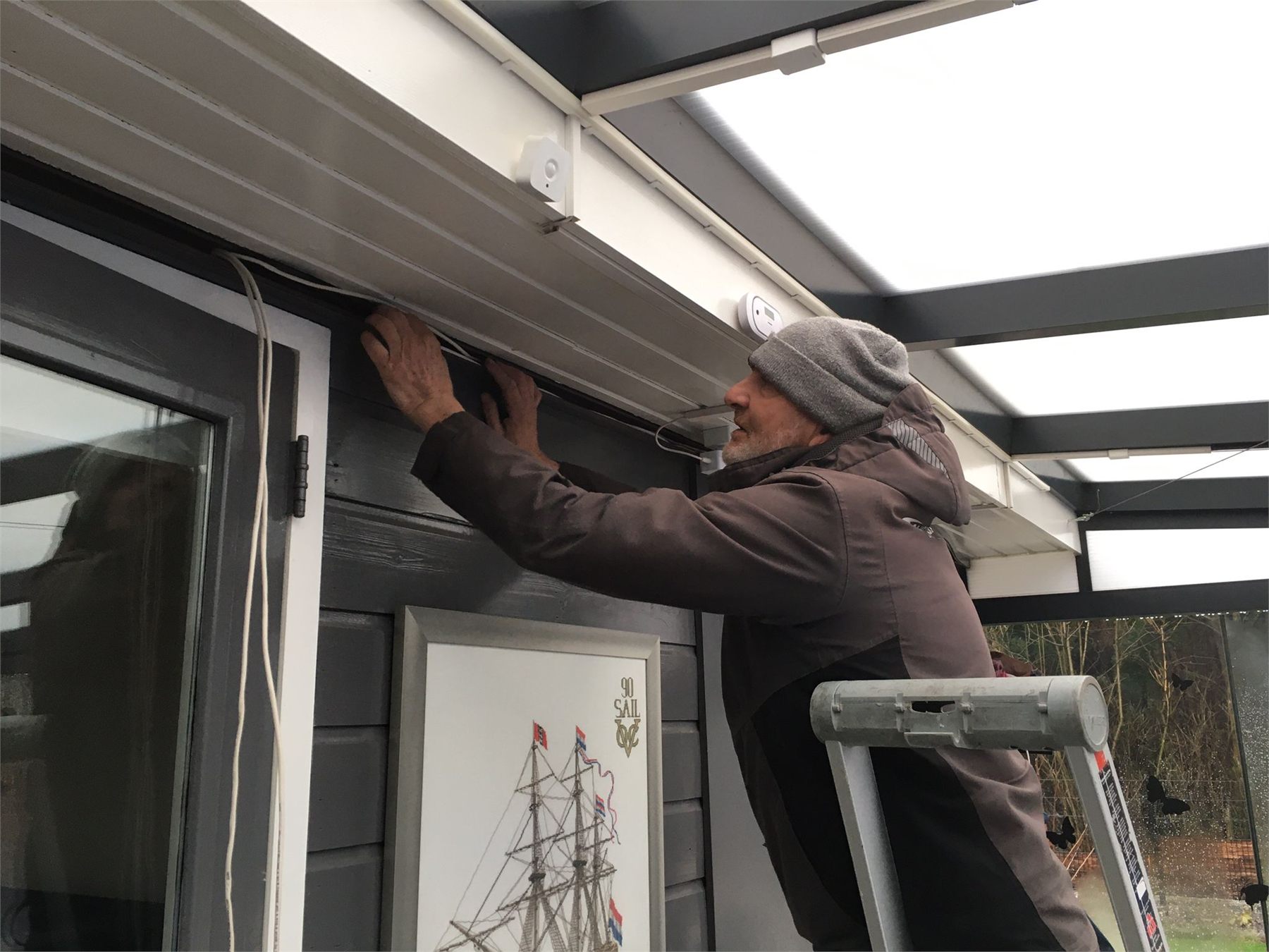 Monteur installeert een beveiligingscamera onder een veranda.