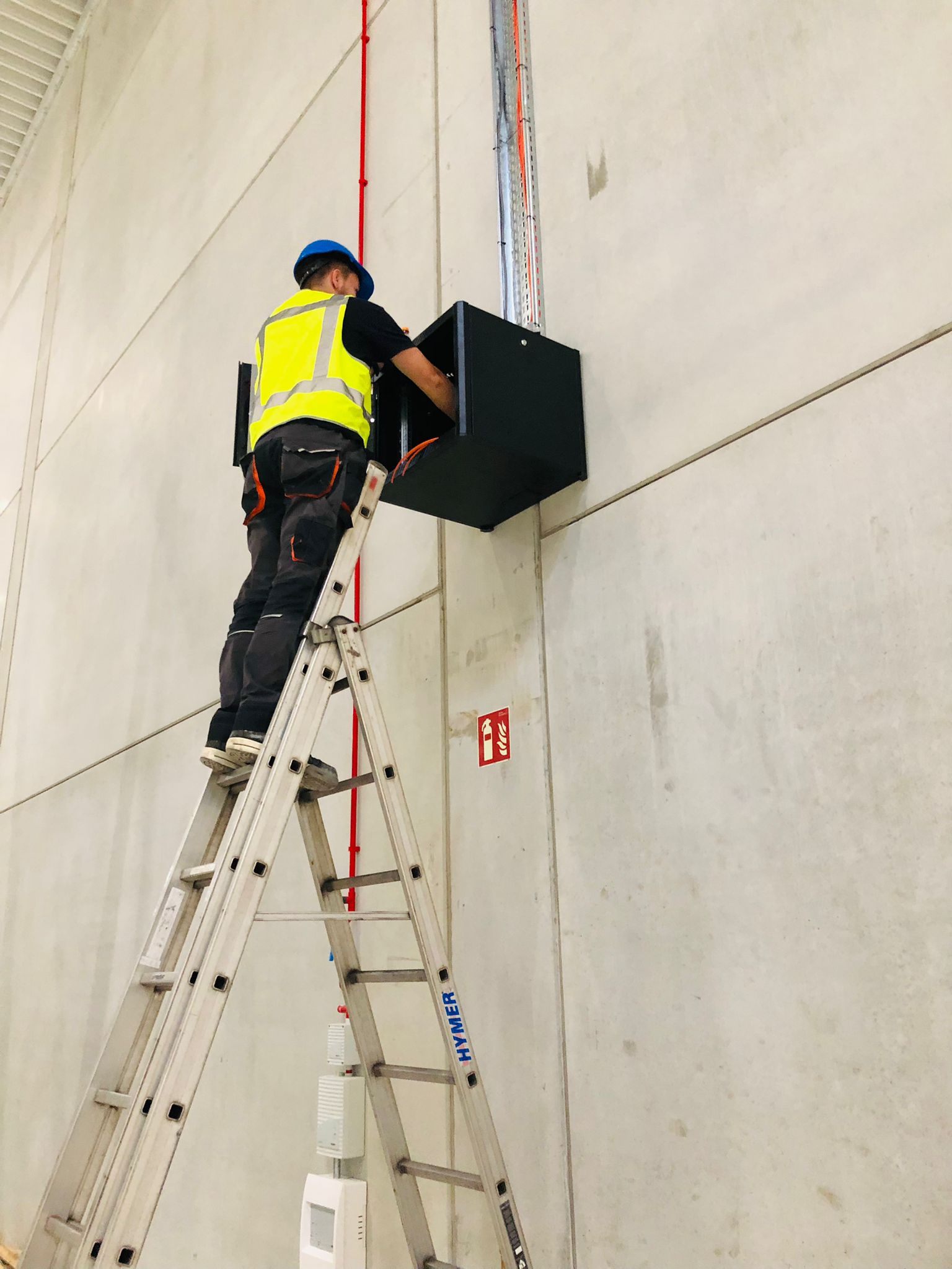Monteur op een ladder monteert apparatuur aan het plafond.