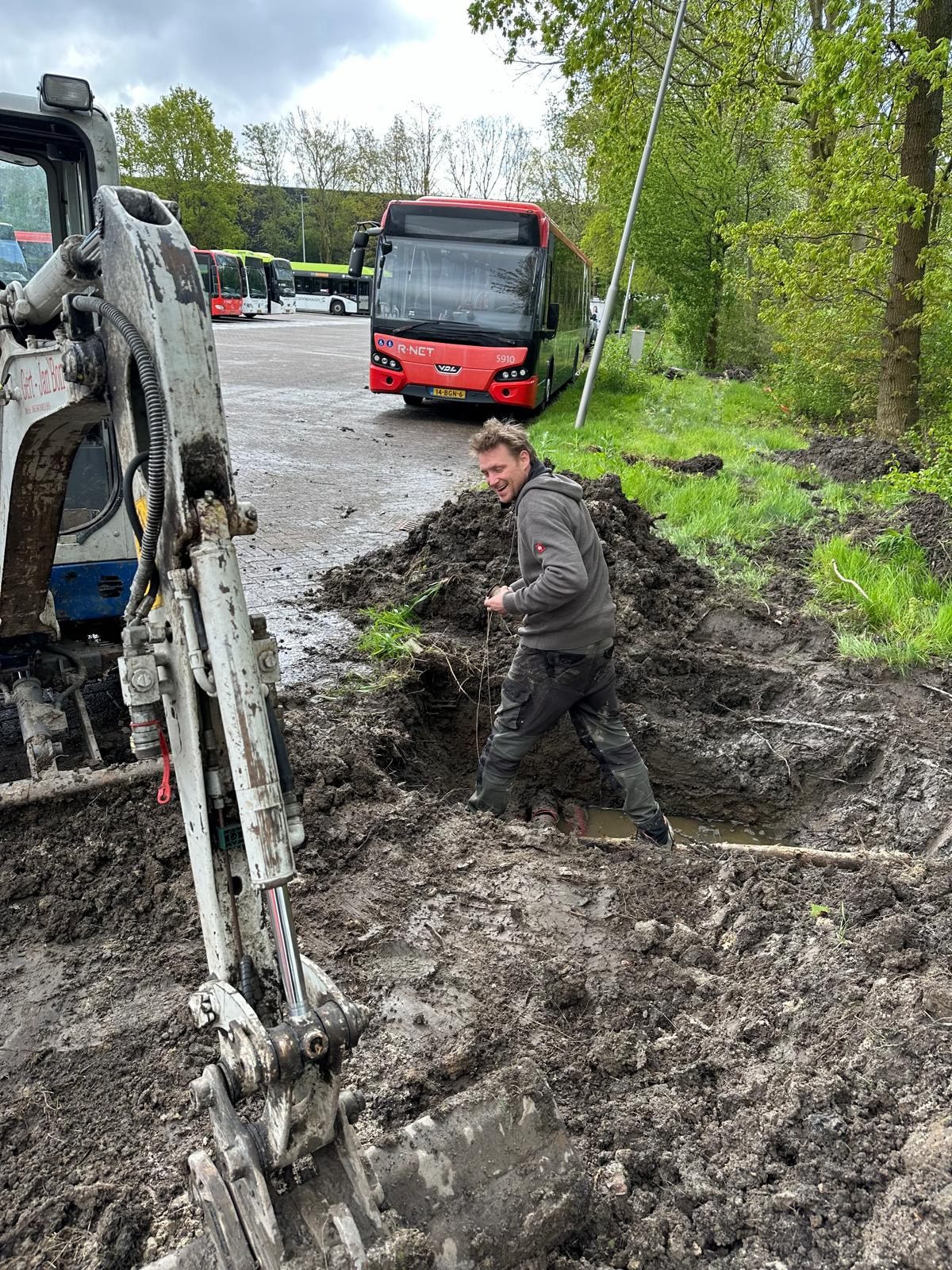 Monteur trekt een kabel in een open sleuf op een terrein.