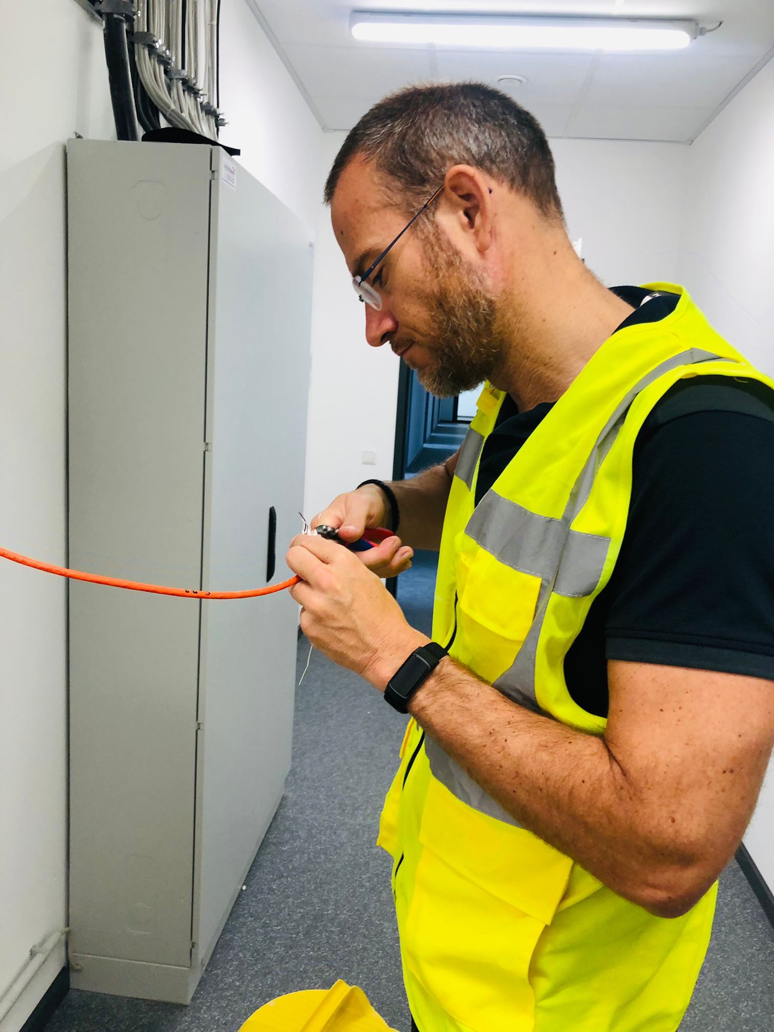 Monteur werkt aan een netwerkkabel in een technische ruimte.