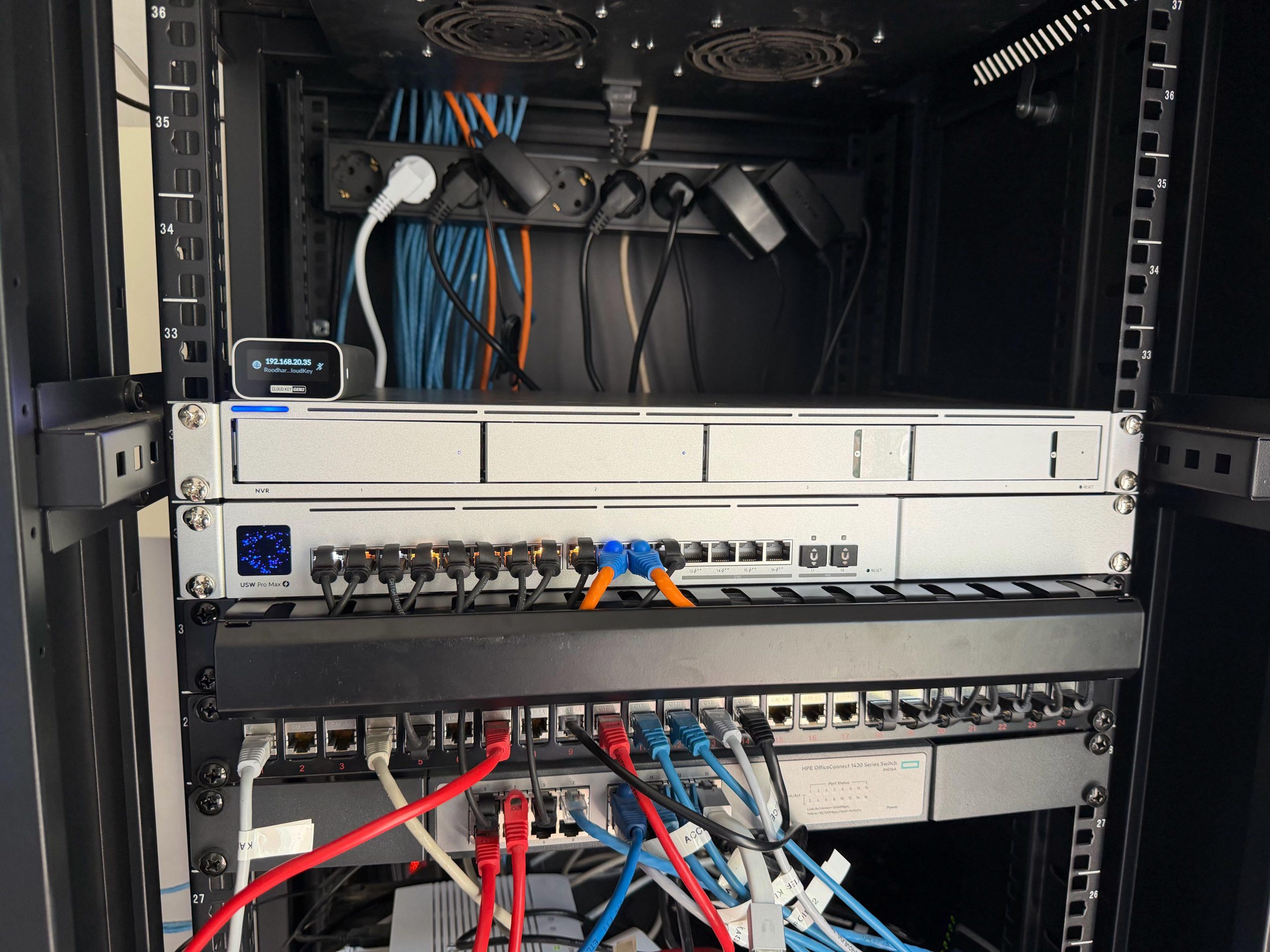 Netwerkkast met een switch, een netwerkvideorecorder en een patchpaneel met gekleurde patchkabels.