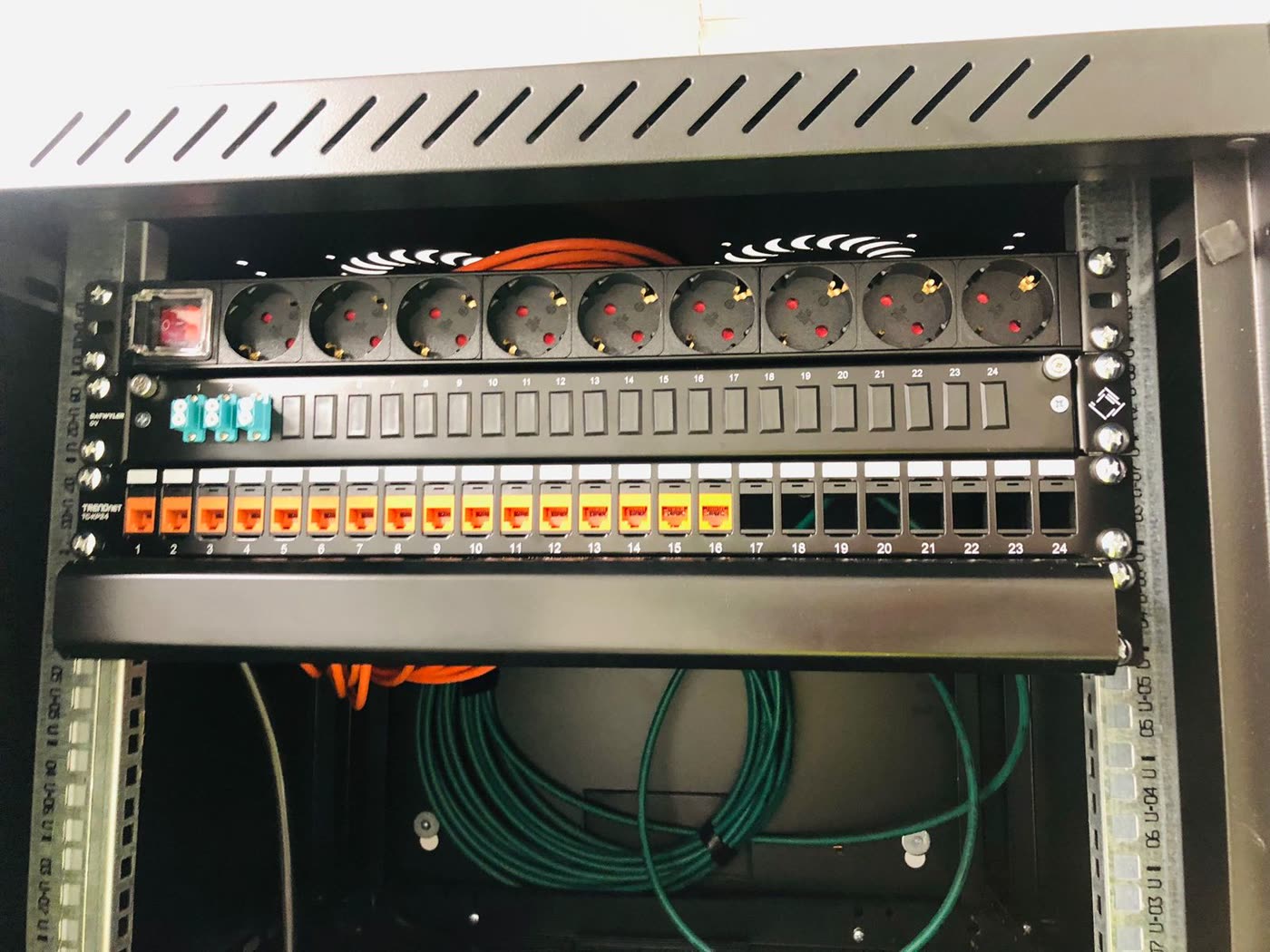 Patchpaneel met stroomverdeling en glasvezel in een serverkast.