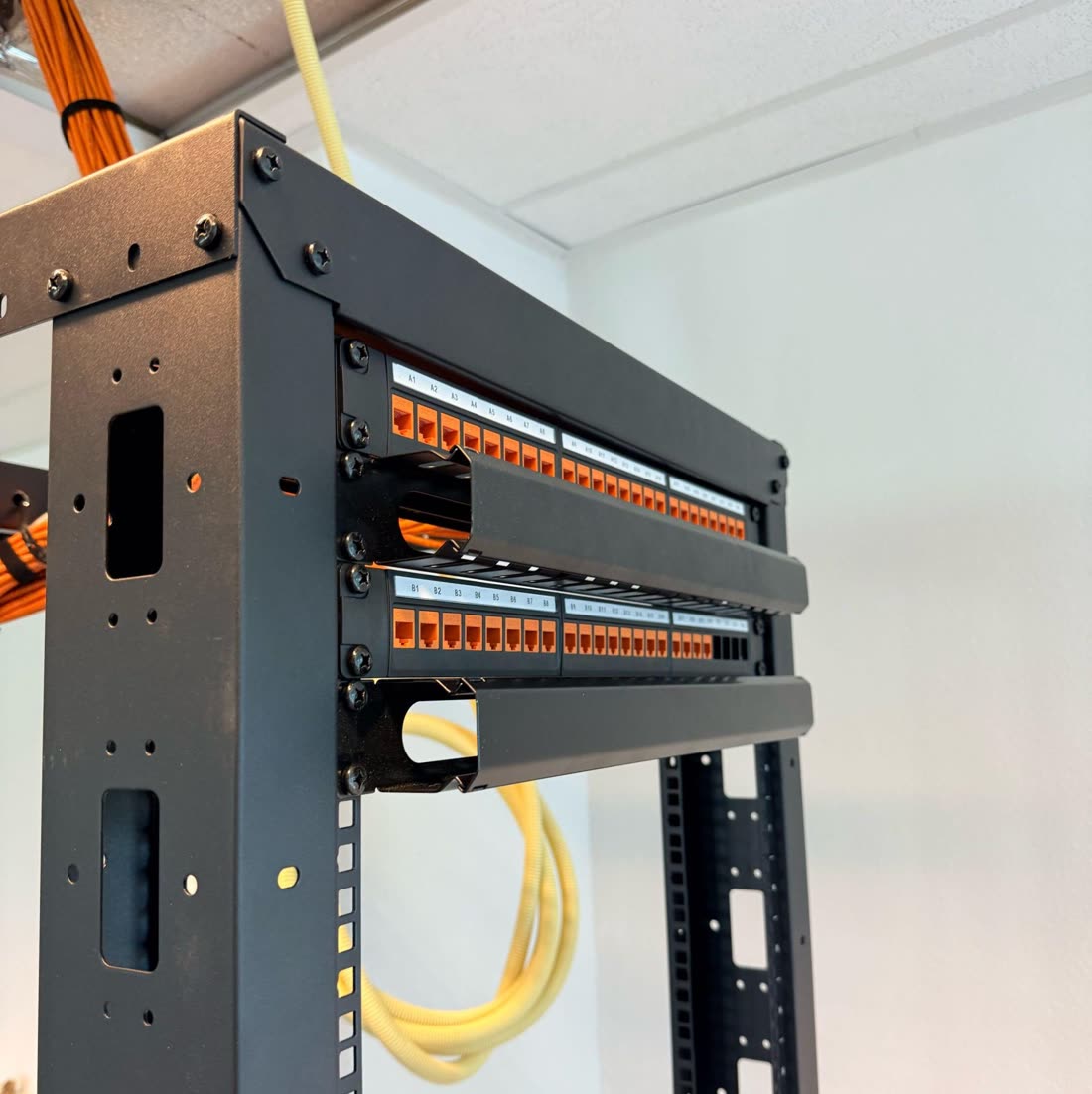 Patchpanelen in een open rack met glasvezel en datakabels.