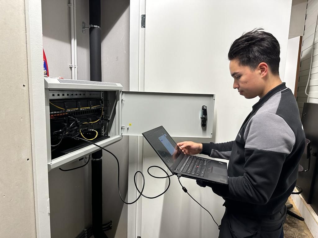 Technicus configureert netwerkapparatuur met een laptop.
