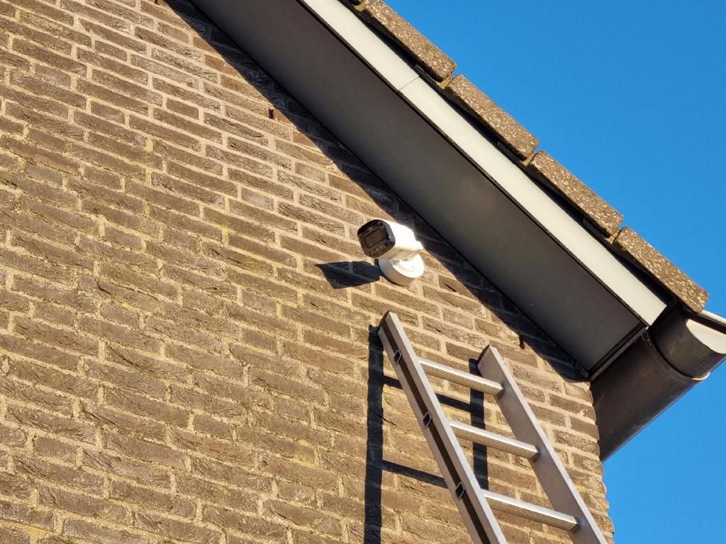 Twee beveiligingscameras aan de bakstenen gevel van een woning.
