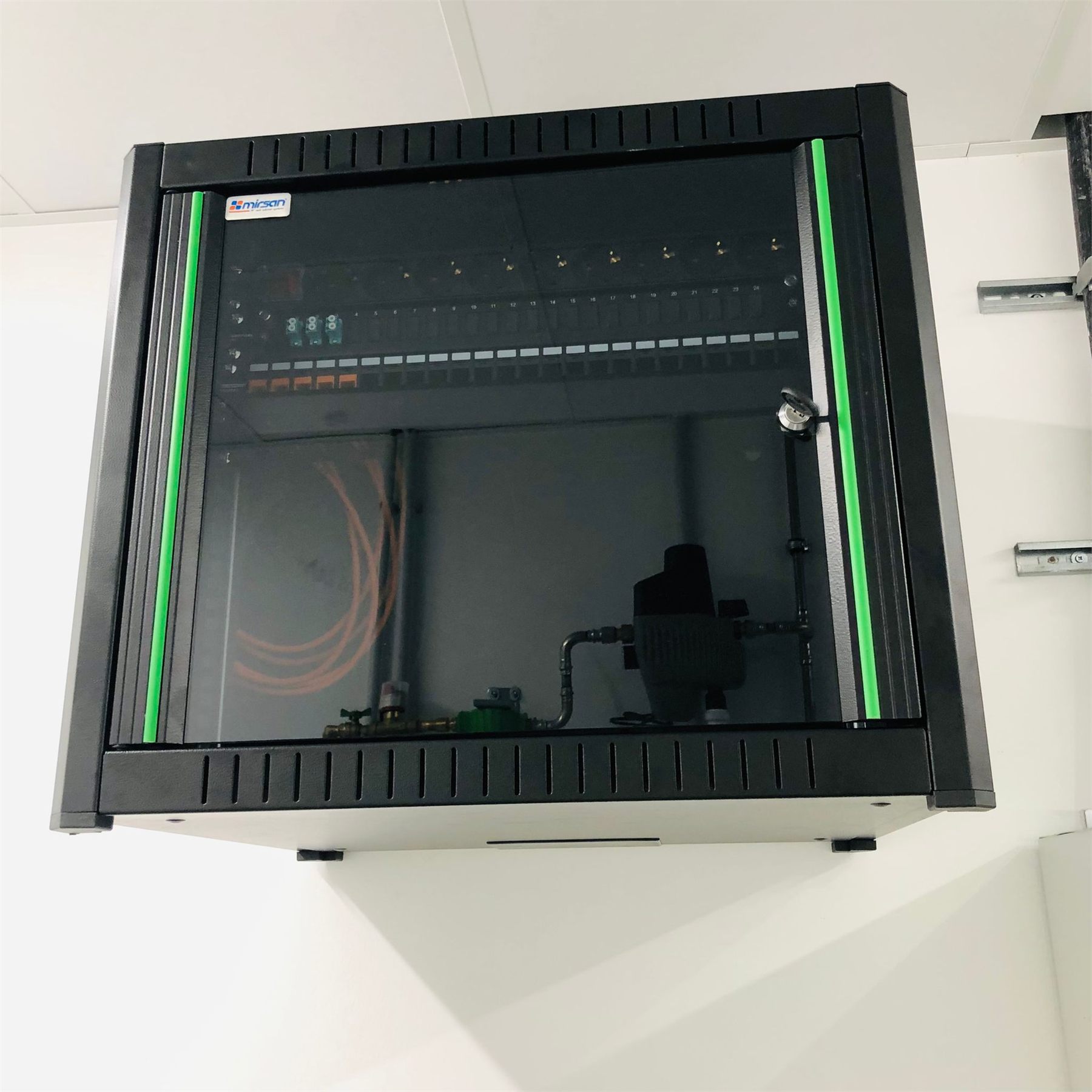 Wandpatchkast met netwerkkabels en groene statusverlichting.