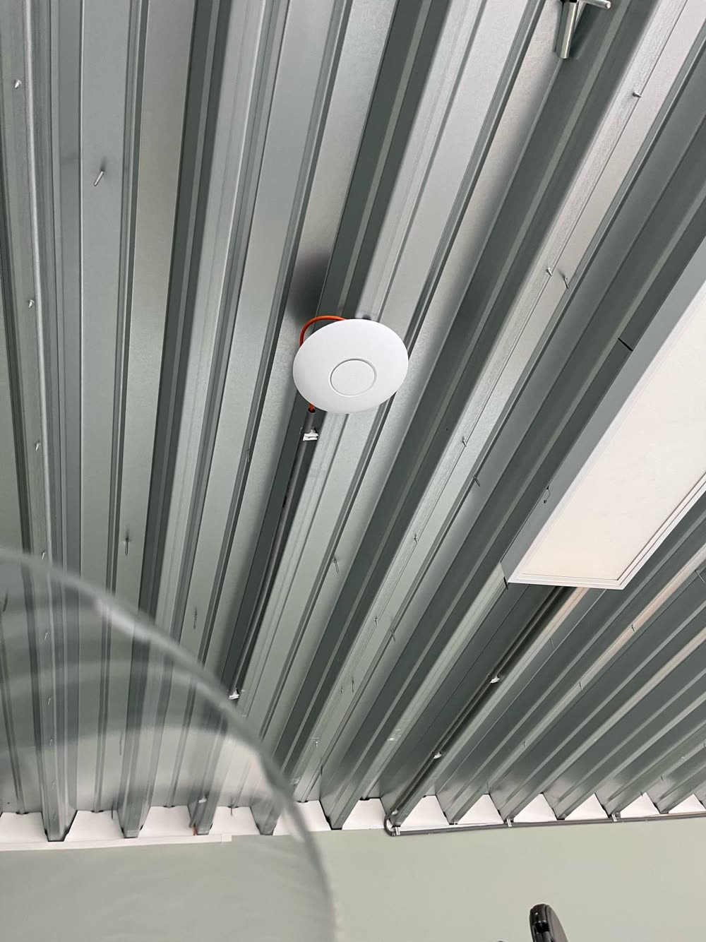 Wifi-accesspoint in een fabriekshal met magazijnstellingen.