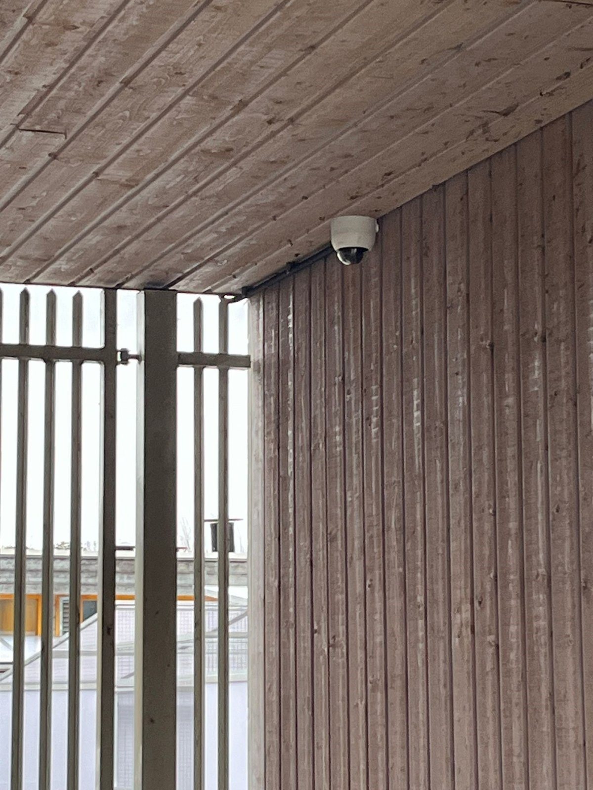 Domecamera onder een houten overkapping bij de looproute langs het hekwerk.