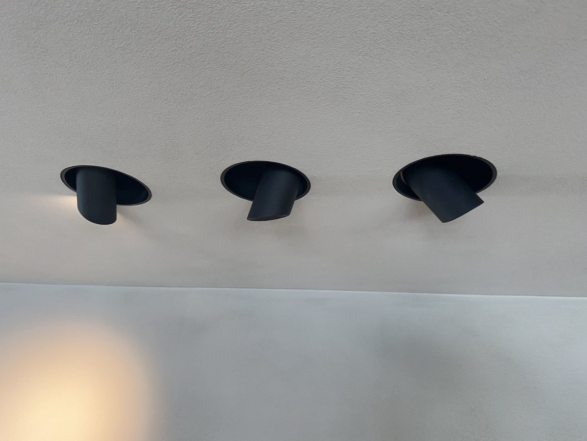 Drie zwarte richtbare inbouwspots in een plafond, elk in een andere stand gedraaid.
