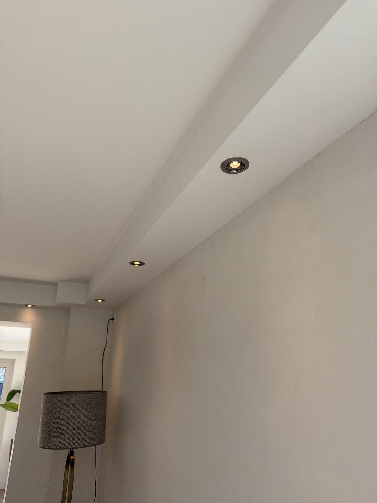 Kantelbare inbouwspots in een verlaagd plafond langs de wand.