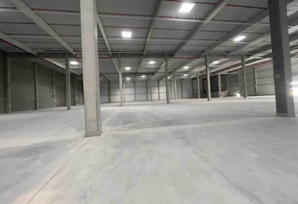 Lege nieuwe bedrijfshal met kaal beton, voordat er iets is aangesloten.