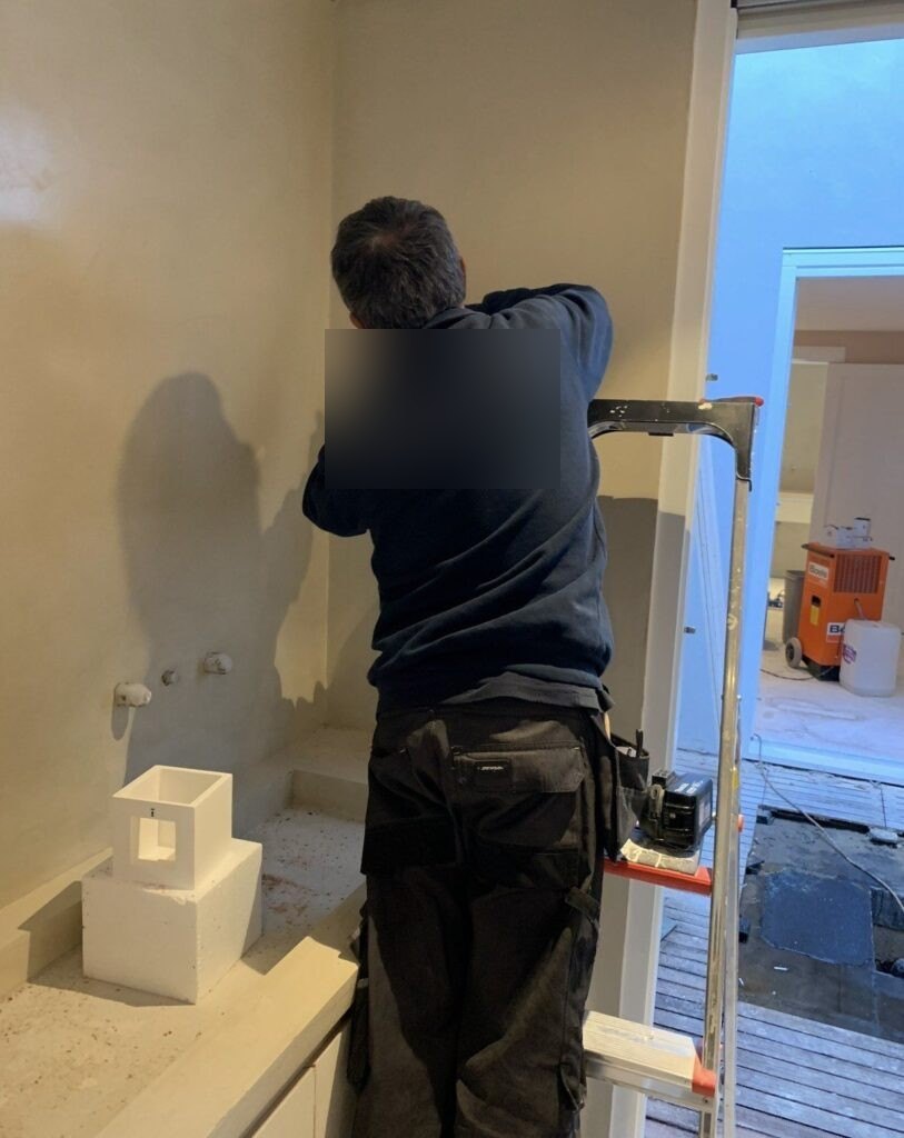Monteur op een trap werkt de aansluitingen in de wand af voordat de stukadoor komt.