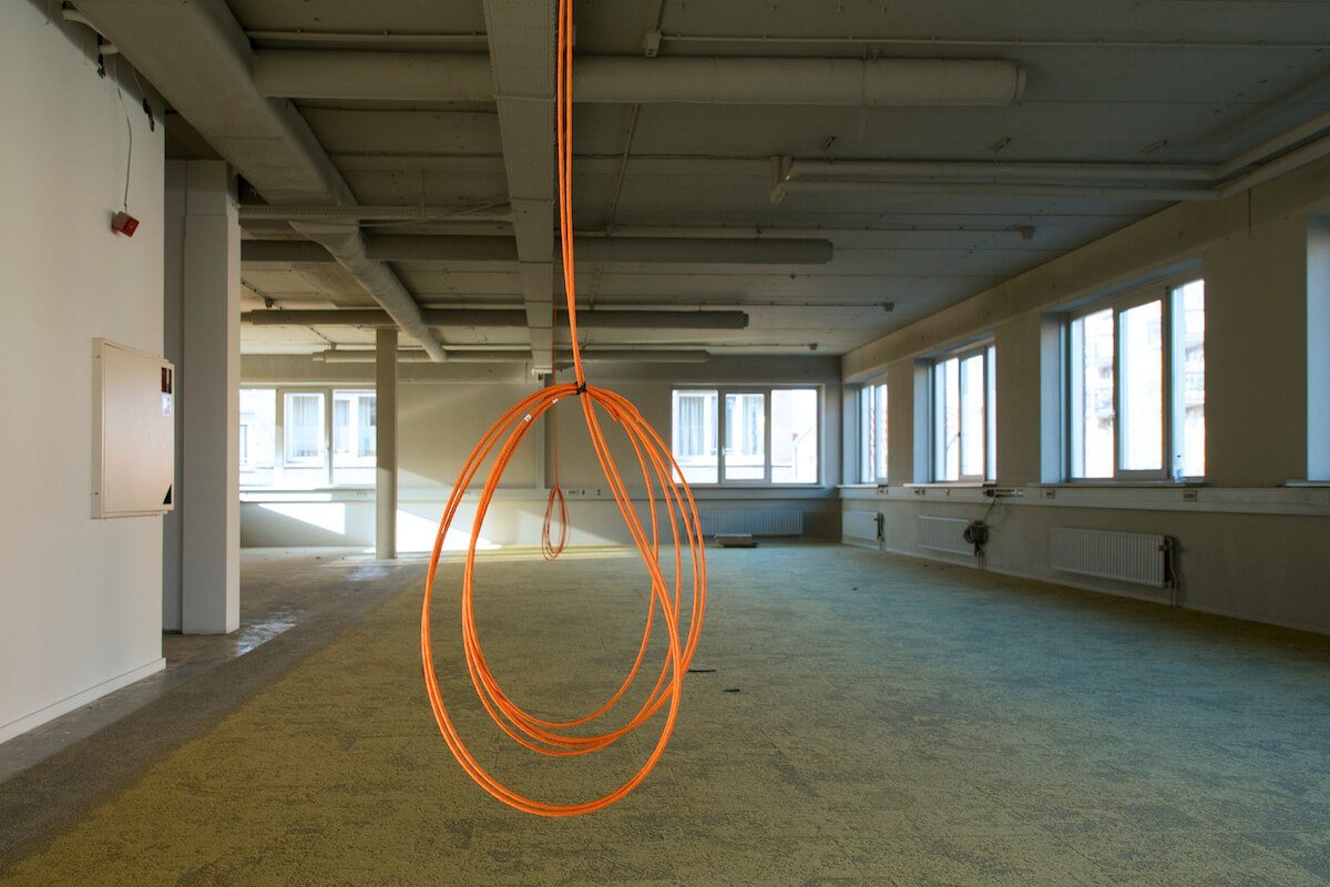 Oranje netwerkkabel die uit het plafond hangt in een lege verdieping.