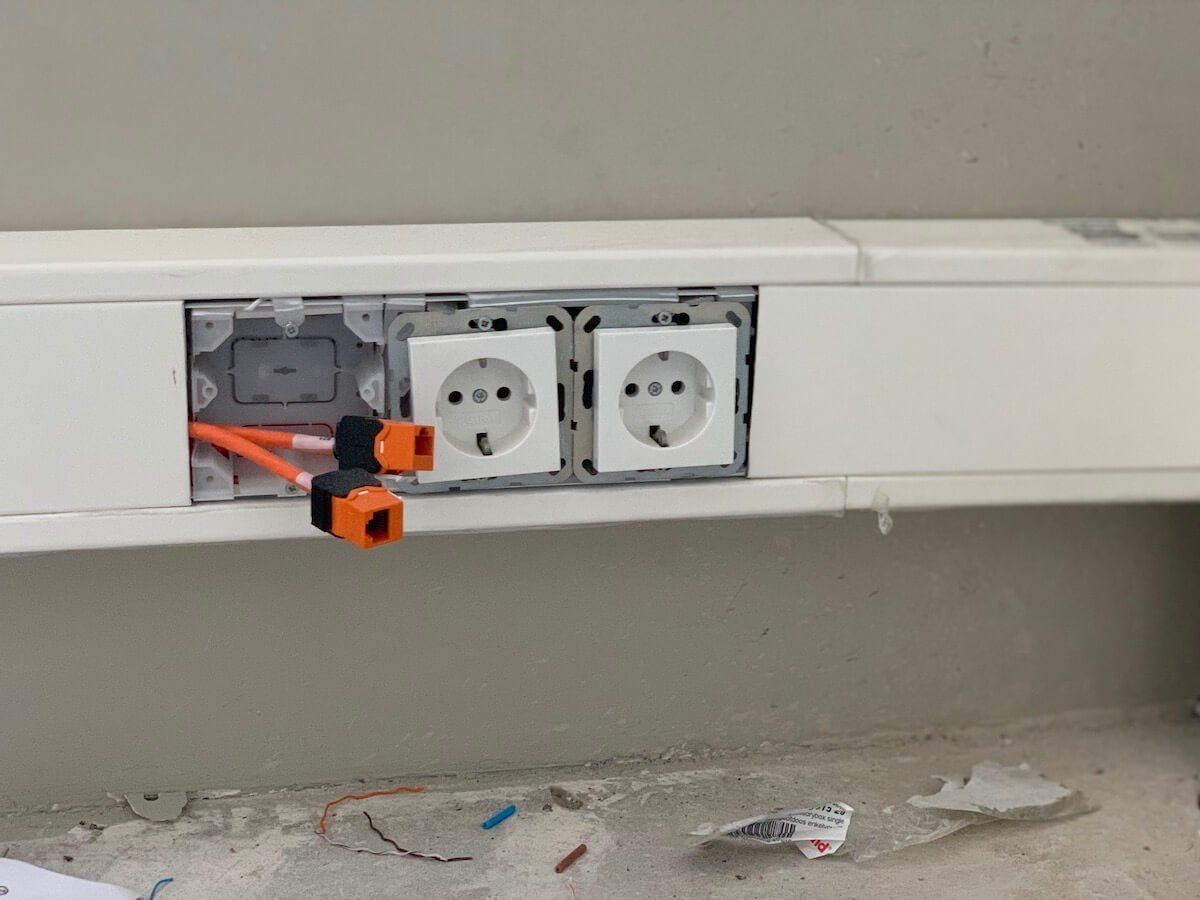 Stopcontacten en oranje keystones in dezelfde kabelgoot, tijdens de afbouw.