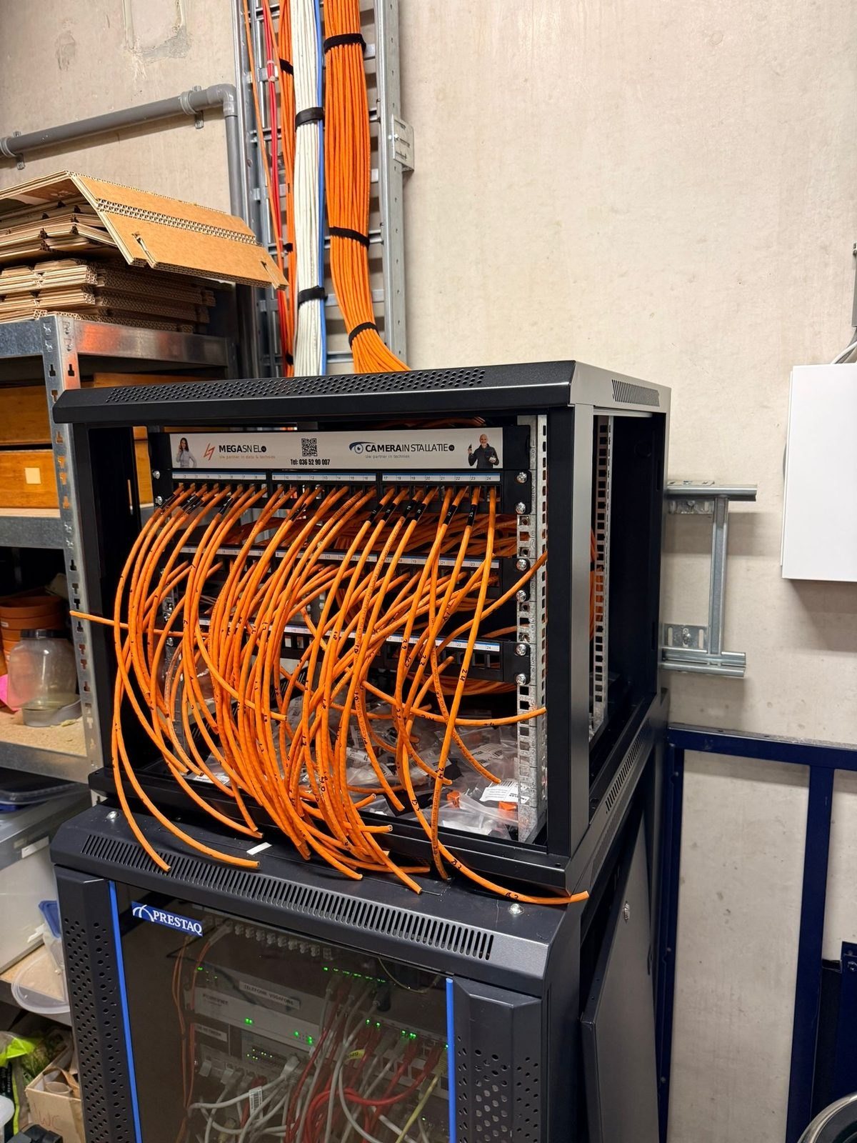 Technische kast met oranje bekabeling, opgebouwd op een standaard.